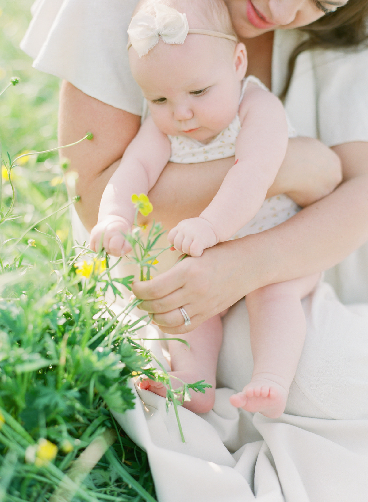 Kent-Avenue-Photography-Charlotte-Newborn-Photographers-On-Film-Mom-sitting-with-baby-reaching-for-flowers