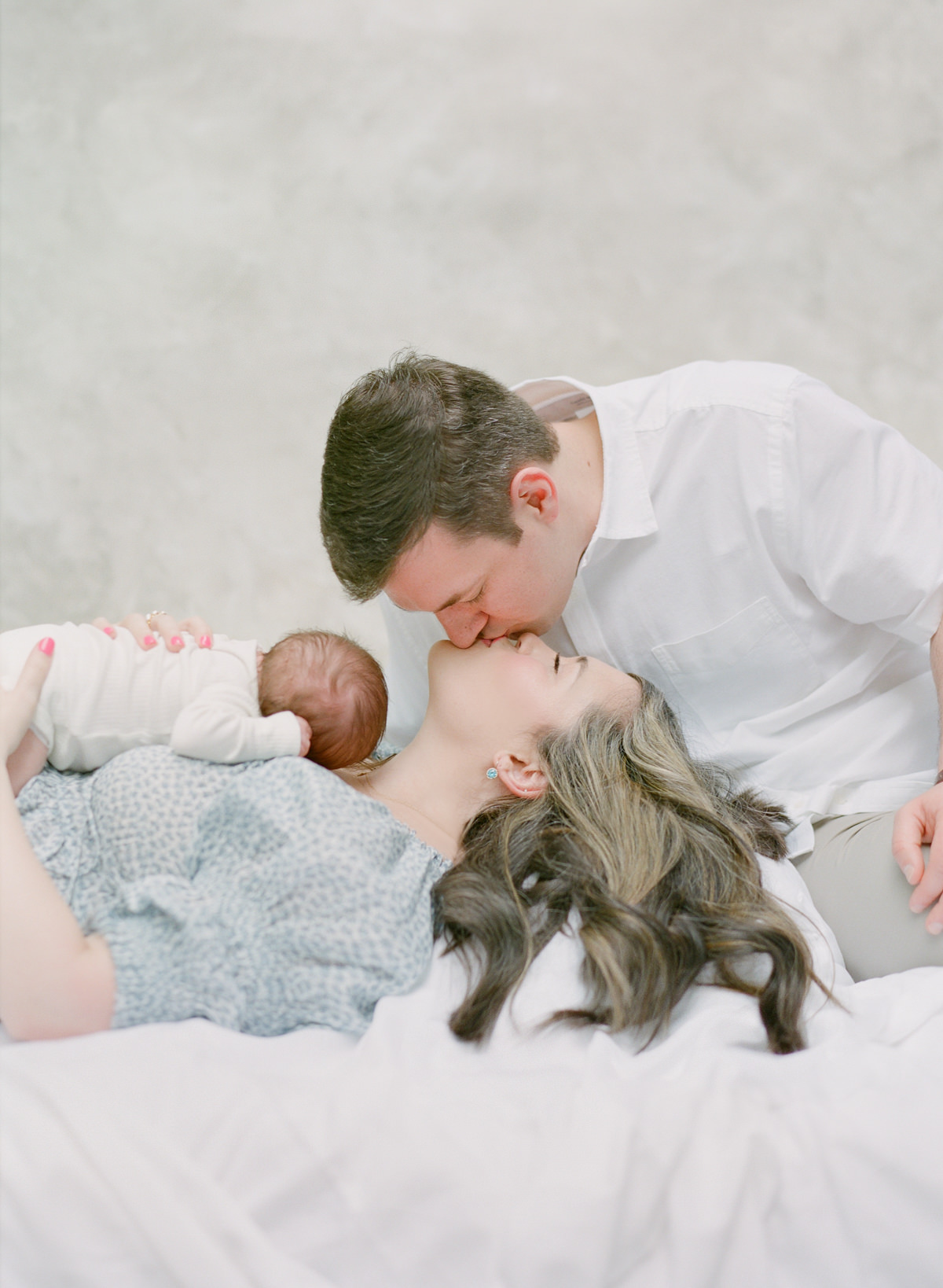 Charlotte Newborn Photography on Film - Mom and Dad Kissing With Baby on Mother's Chest - Kent Avenue Photography