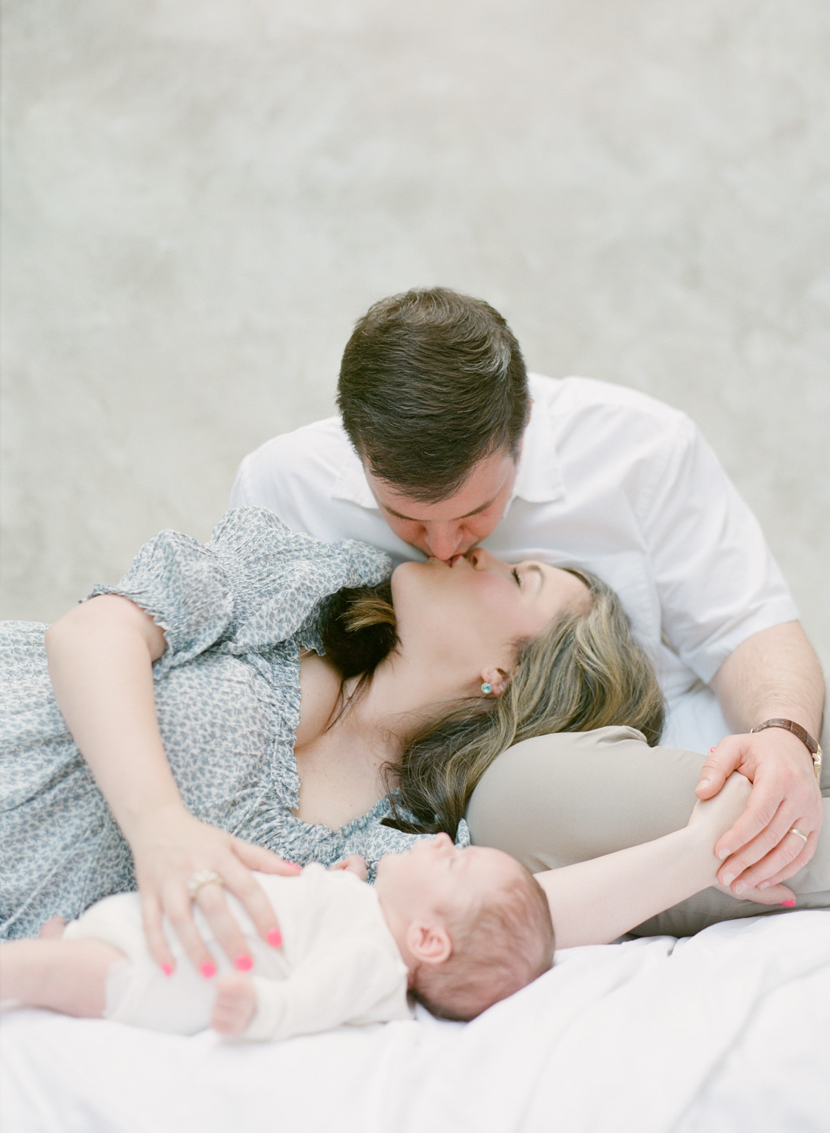 Charlotte Newborn Photography On Film -Mom and Dad Kissing With Baby - Kent Avenue Photography