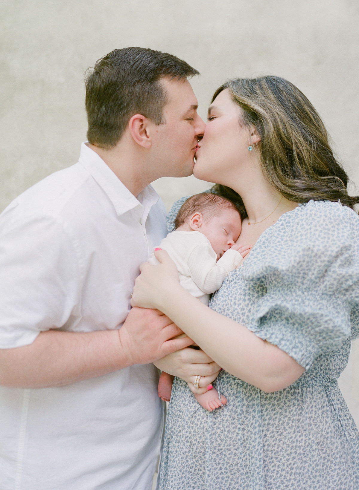Charlotte Newborn Photographer - Mom and Dad Kissing with baby - Kent Avenue Photography